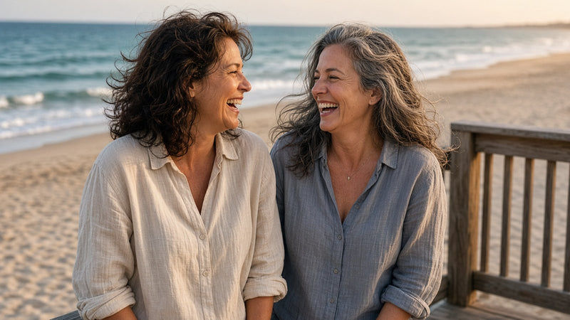 Two friends laughing together on a beach boardwalk